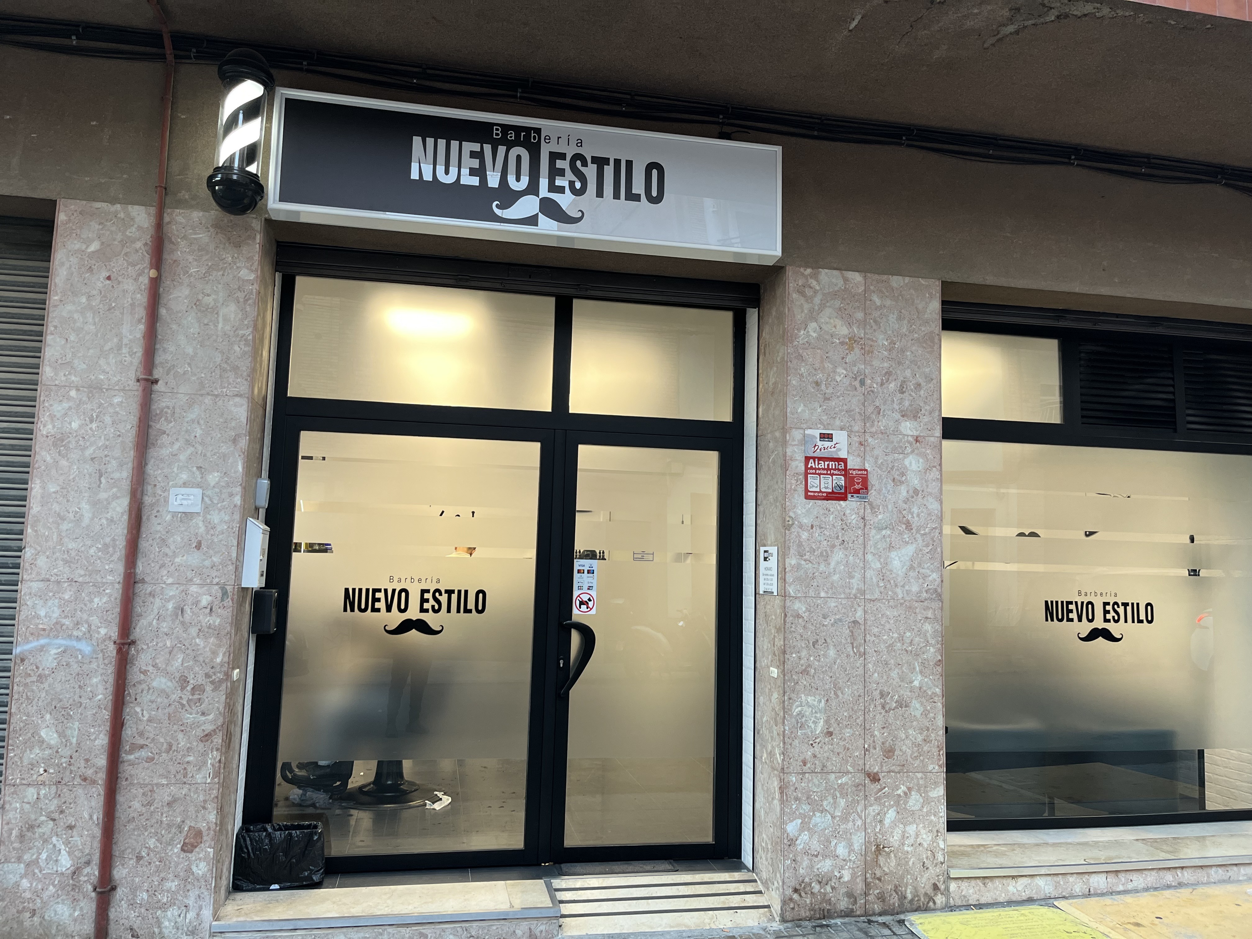 Fachada de la barbería en la calle Barcelona con el rótulo NUEVO ESTILO sobre el escaparate.