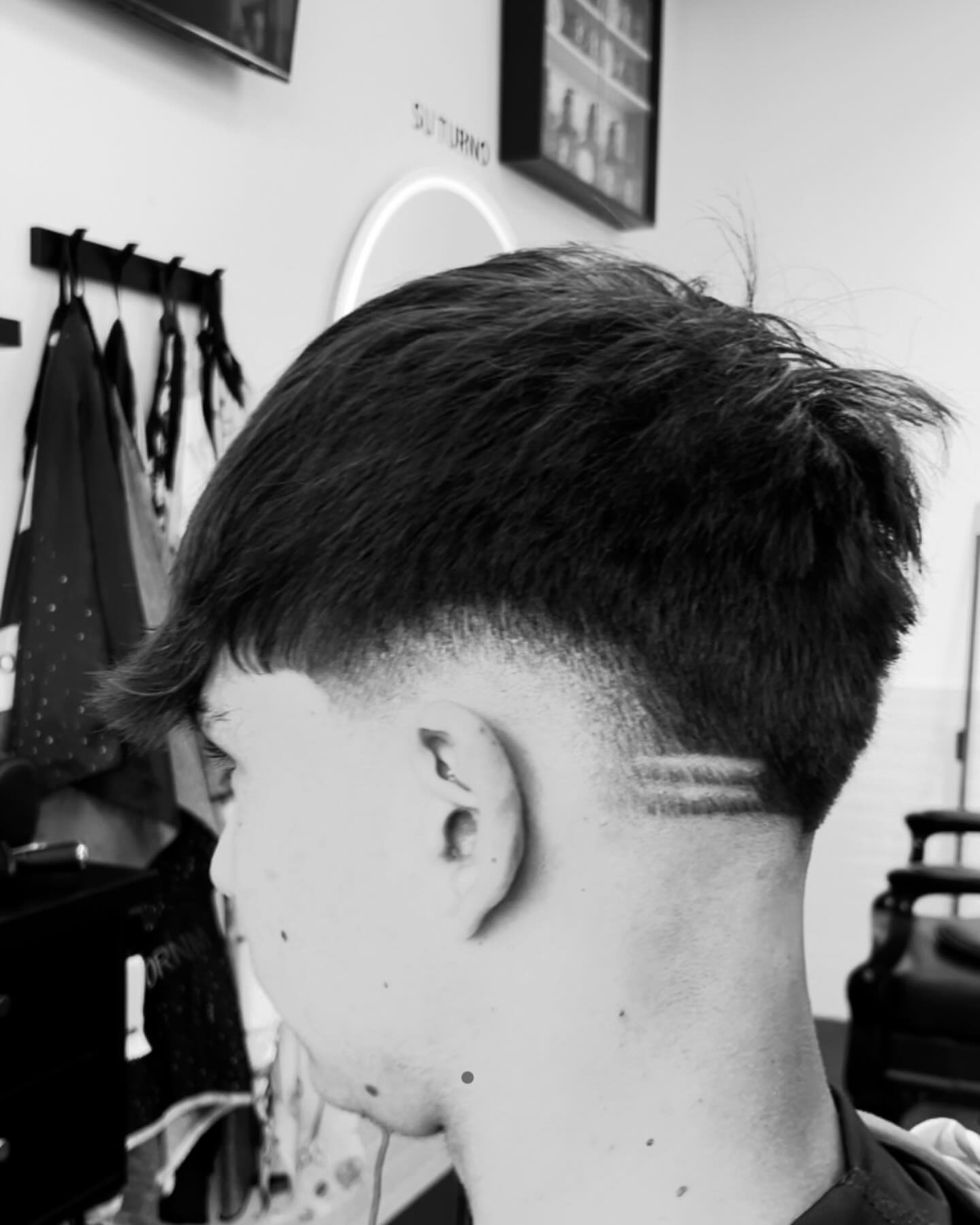 Dos líneas marcadas a máquina sobre la oreja, en blanco y negro.